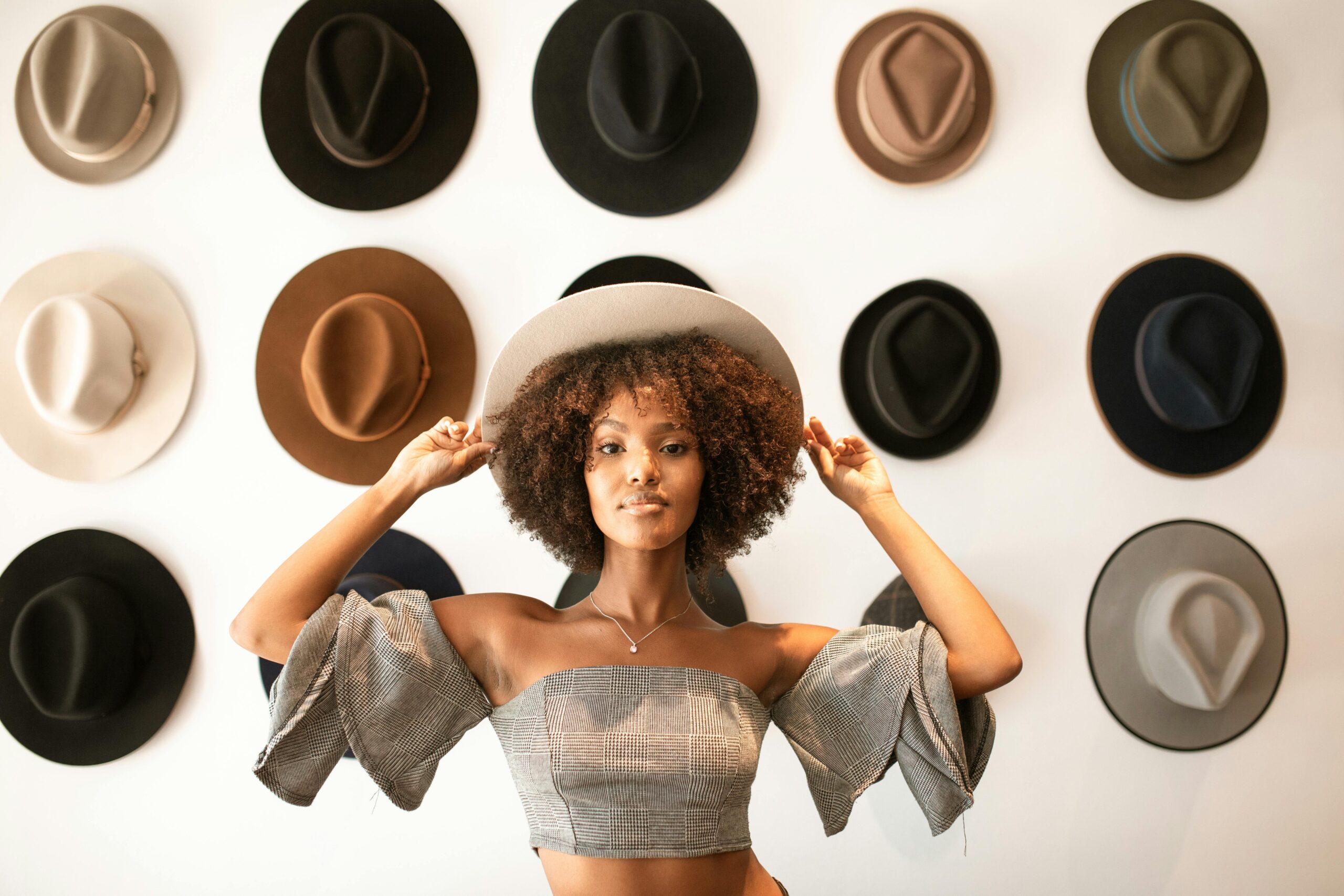 une femme qui porte un chapeau, qui illustre notre guide chapeau. Il y a des chapeaux en fond.
